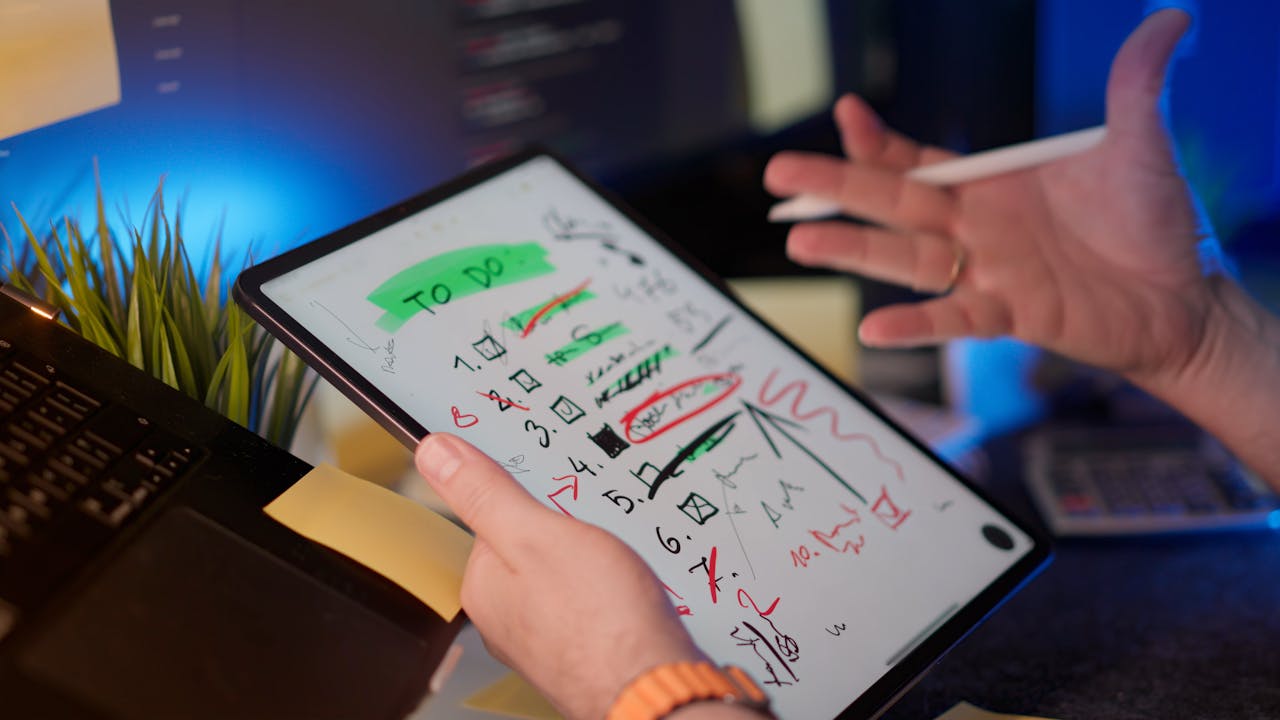 A person managing tasks on a tablet with a digital pen in a modern office setting.